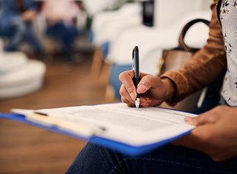 Woman filling out dental insurance form in lobby