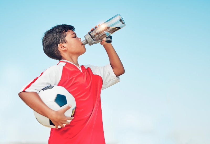 Child soccer player drinks water